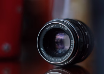 Macro shot of a vintage camera lens reflecting colors in soft focus, showcasing classic optics.