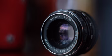 Macro shot of a vintage camera lens reflecting colors in soft focus, showcasing classic optics.
