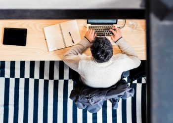 man sitting by the desk using laptop computer