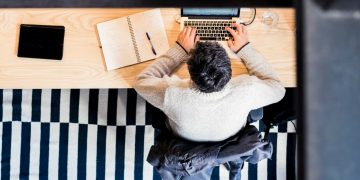 man sitting by the desk using laptop computer