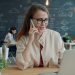 Woman talking on phone at desk with laptop