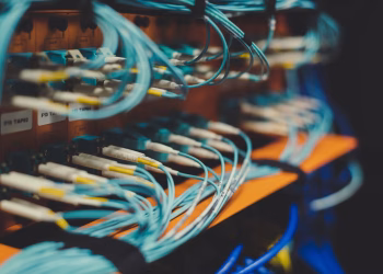 Closeup of many cables with blue wires plugged in modern switch with similar adapters on blurred background in modern studio