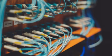 Closeup of many cables with blue wires plugged in modern switch with similar adapters on blurred background in modern studio