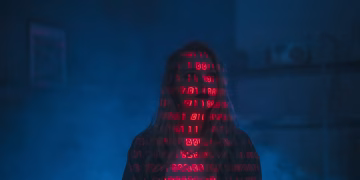 A mysterious silhouette with red binary code projected over the face, set against a dark, moody background.