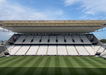 Wide view of an empty football arena in São Paulo, featuring a green pitch under a sunny sky.