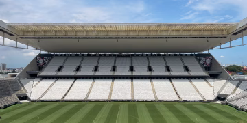 Wide view of an empty football arena in São Paulo, featuring a green pitch under a sunny sky.