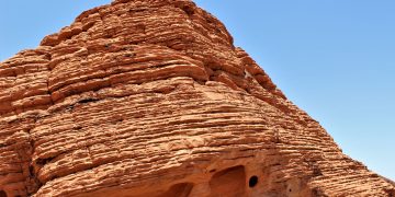 Stunning red rock formations against a clear blue sky, showcasing natural texture patterns.