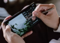 Close-up of a person editing photos on a smartphone with a stylus indoors.