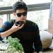 A man wearing sunglasses uses a smartphone's voice assistant in a cozy indoor setting.