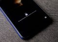 Mobile phone with no face detected message on lock screen on a textured fabric surface.