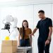 Two engineers collaborating on testing a futuristic robotic prototype in a modern indoor lab.