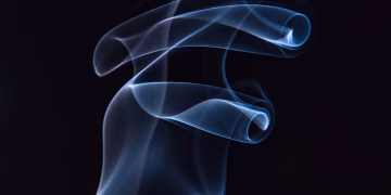 Artistic capture of swirling blue smoke against a black background, highlighting motion and elegance.