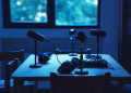 Dimly lit podcast studio with microphones and headphones on a table.