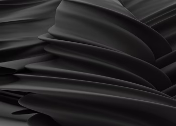 Elegant abstract image of undulating black satin fabric with fluid, smooth folds.