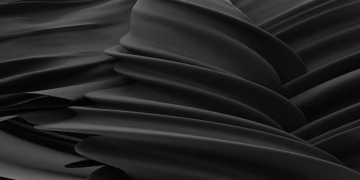 Elegant abstract image of undulating black satin fabric with fluid, smooth folds.