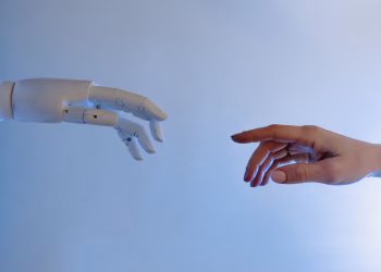 A human hand reaching towards a robotic hand symbolizing technology and connection.
