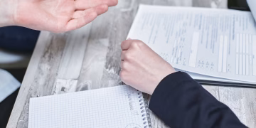 Professional office discussion at desk with documents and note taking.