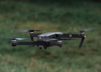 A drone in flight outdoors, showcasing its sleek design and spinning rotors.