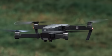 A drone in flight outdoors, showcasing its sleek design and spinning rotors.