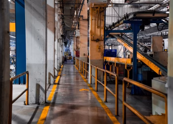 Wide view of a modern factory interior showcasing industrial machinery and conveyor systems.