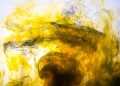 Dynamic abstract image of yellow ink swirling in water, creating mesmerising patterns.