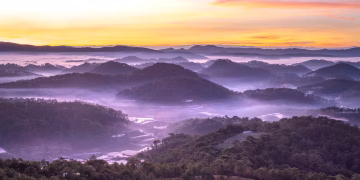 Capture the serenity of a misty mountain landscape at sunrise with vibrant colors and tranquil scenery.