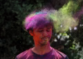 Capture of a man celebrating Holi with vibrant colored powder outdoors.