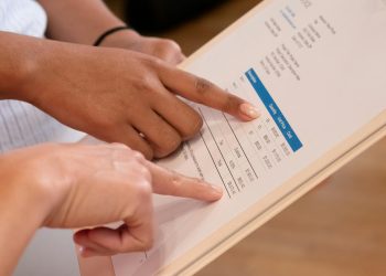Two people pointing at financial details on a document, highlighting invoice analysis.