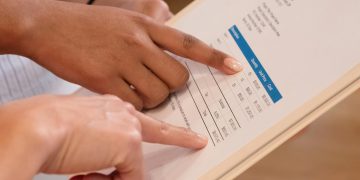 Two people pointing at financial details on a document, highlighting invoice analysis.