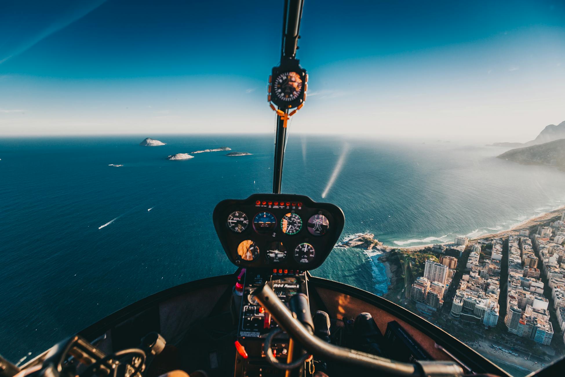 Aerial view from helicopter cockpit over Rio de Janeiro coastline and ocean.