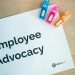 Colorful office stationery featuring quirky clips and 'Employee Advocacy' sign on a desk.