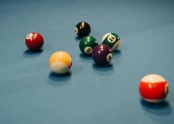 Colorful billiard balls scattered on a blue pool table, capturing a vibrant moment of still life.