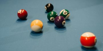 Colorful billiard balls scattered on a blue pool table, capturing a vibrant moment of still life.