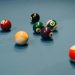 Colorful billiard balls scattered on a blue pool table, capturing a vibrant moment of still life.