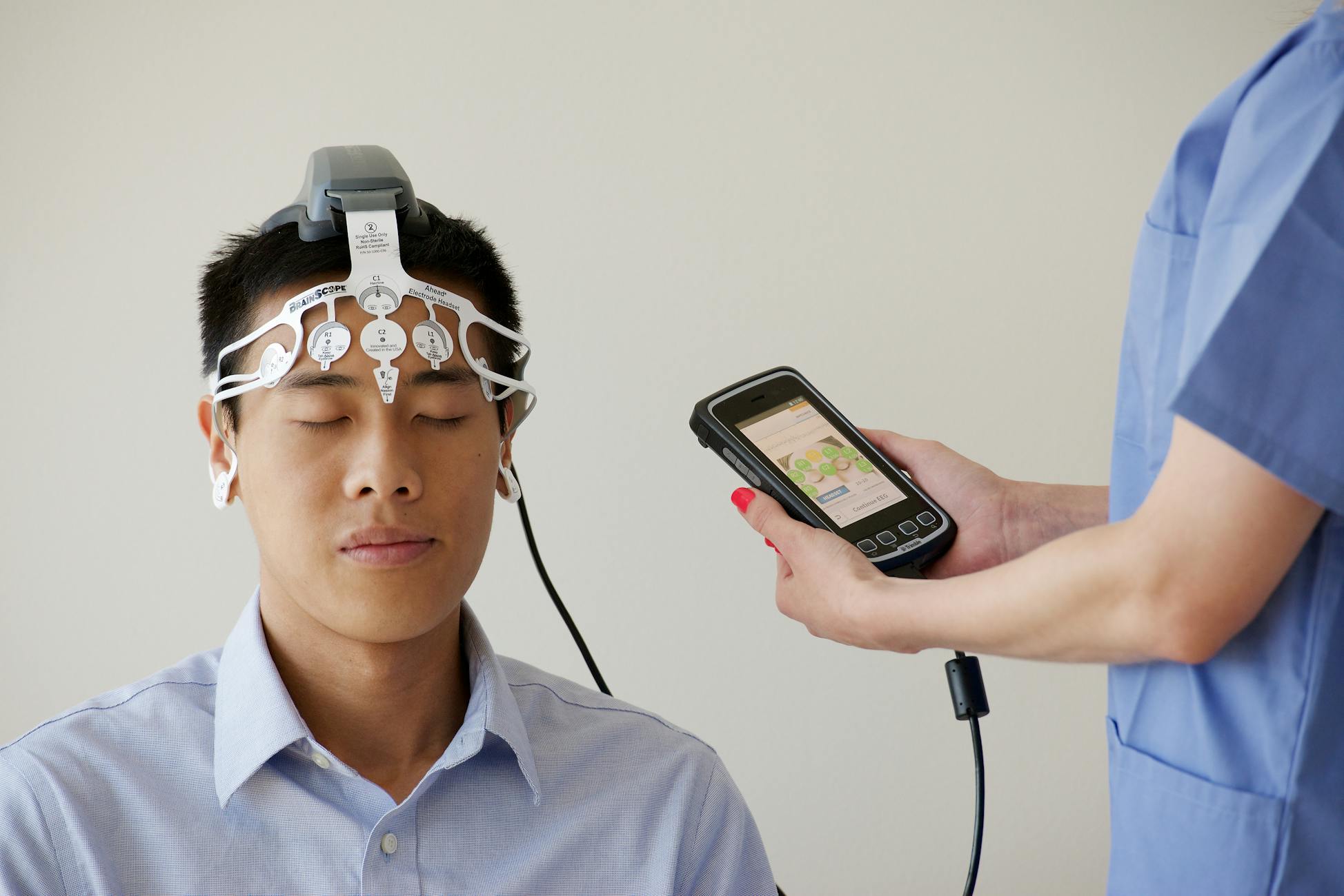 Healthcare professional conducting an EEG examination using a Brainscope device on a male patient.