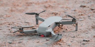 Close-up of a modern drone resting on sandy terrain, highlighting technology and exploration.