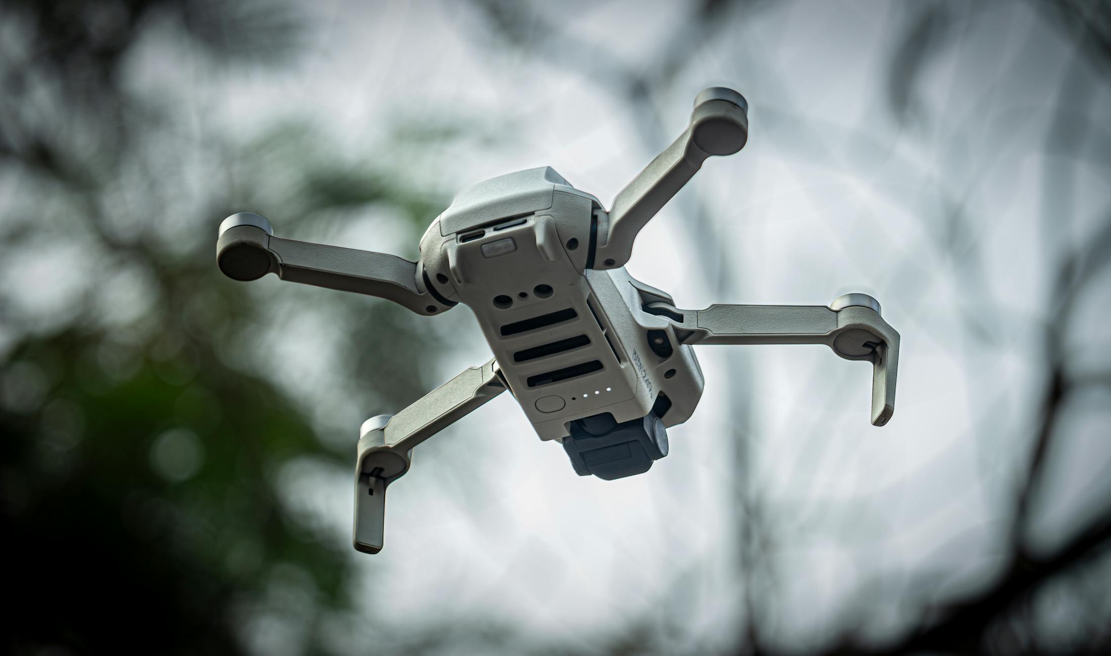 A sleek drone flying against a blurred outdoor background in Dhaka, Bangladesh.