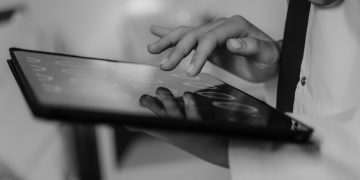 Close-up of a doctor's hand using a touchscreen tablet, highlighting digital healthcare technology.