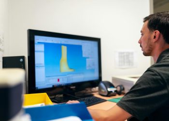 Engineer working on prosthetic design using specialized software in an office setting.