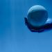 A robotic hand holds a glowing celestial sphere against a blue background, evoking a futuristic theme.