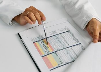 Doctor hands examining and pointing at medical charts in a close-up view.