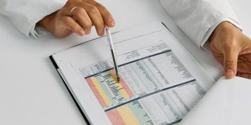 Doctor hands examining and pointing at medical charts in a close-up view.