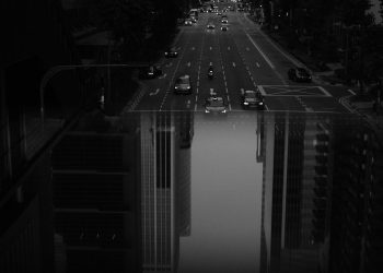 Black and white cars driving on road with double exposure of high skyscrapers in modern city downtown