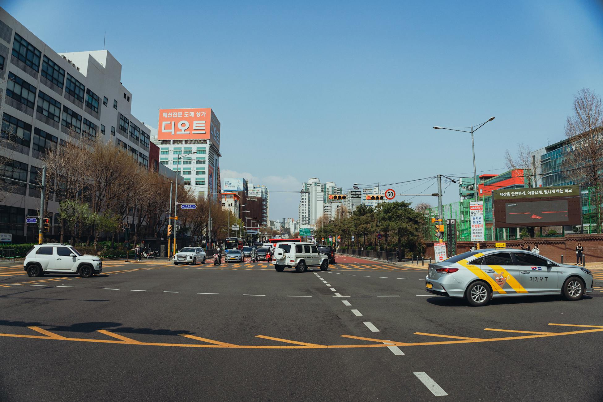 Street view of a busy intersection in Seoul, South Korea with cars and pedestrians.