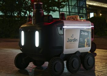 Close-up view of an autonomous delivery robot on a city street at night under artificial light.
