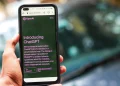 Close-up of a smartphone showing ChatGPT details on the OpenAI website, held by a person.