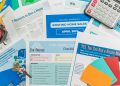 Flat lay of real estate brochures, checklists, and a calculator for home buying.