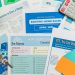 Flat lay of real estate brochures, checklists, and a calculator for home buying.