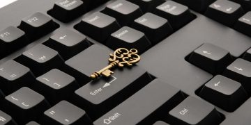 Close-up of an ornate vintage key placed on a modern computer keyboard.