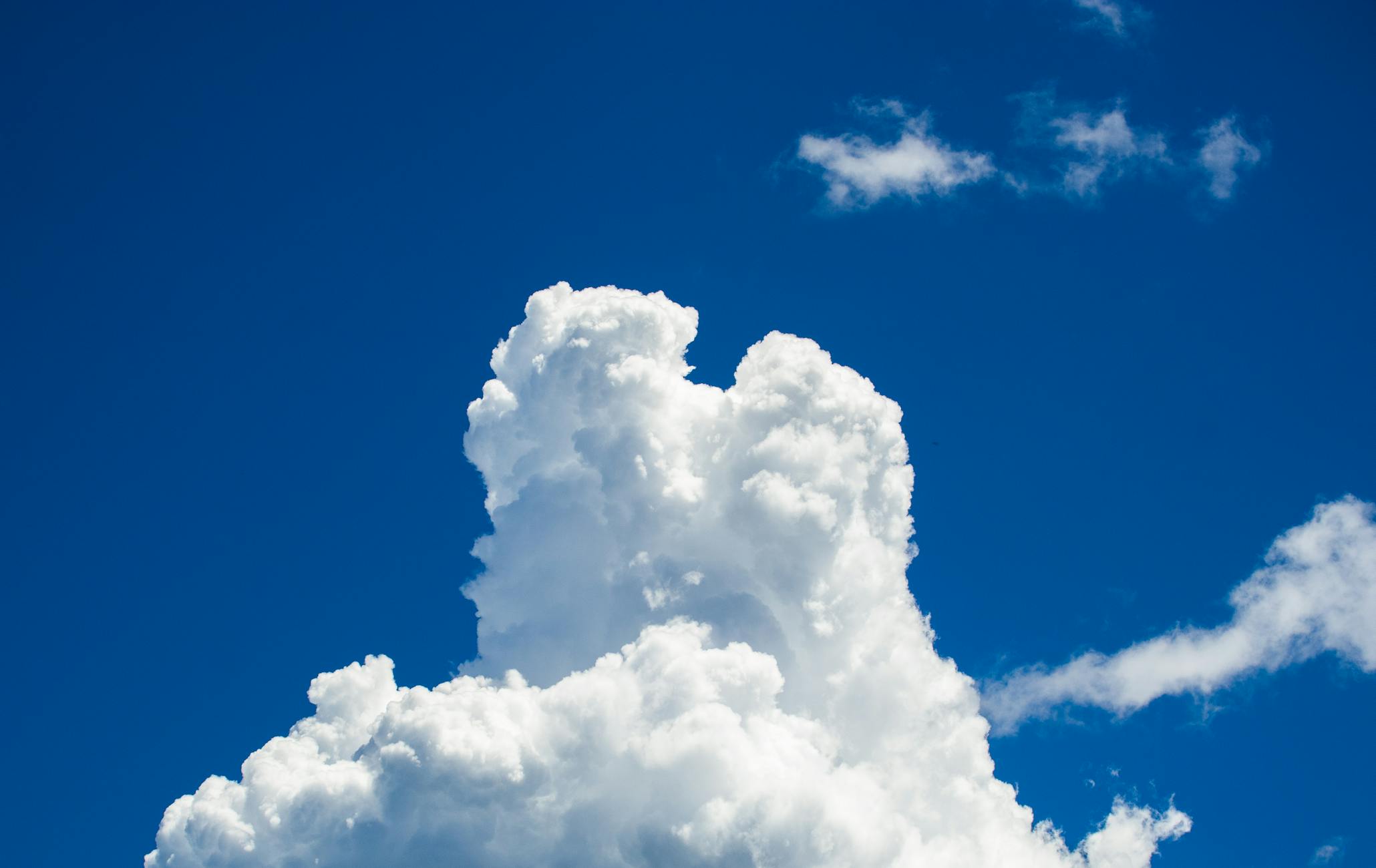 A towering white cloud with a vivid blue sky backdrop, showcasing nature's beauty.